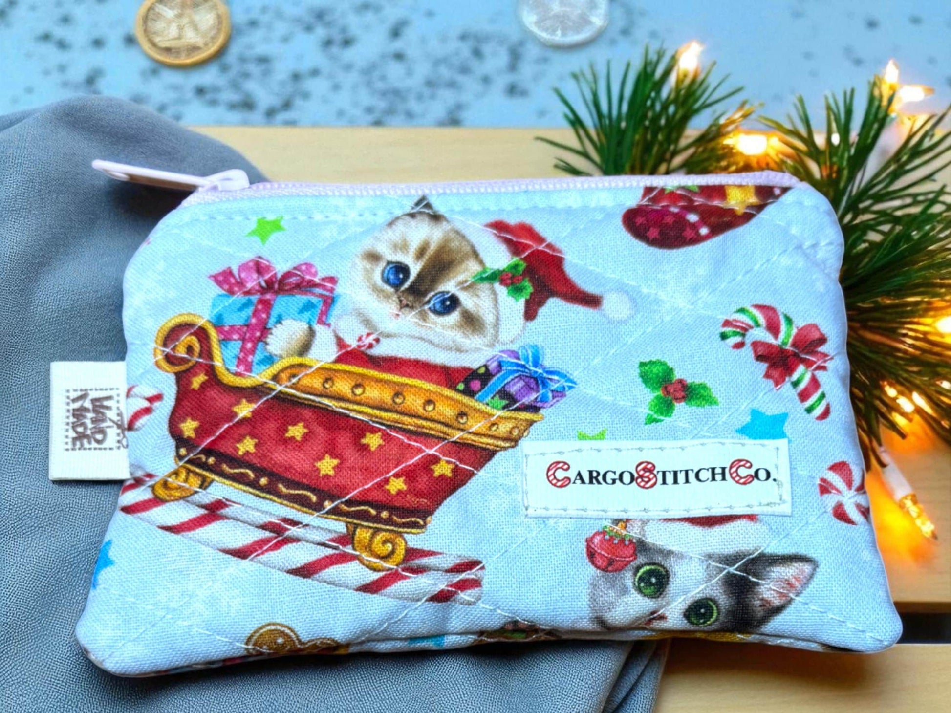 Quilted 5×3 pouch with holiday cat in sleigh print, light blue background and pink zipper, no pocket — handmade Peppermint Lane Everyday collection bag.